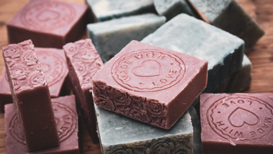 An image of artisan soap cut into small bars stamped with 'made with love'