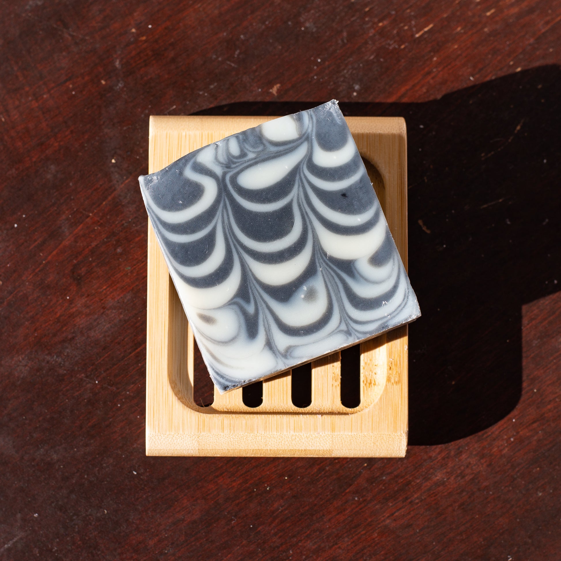 a black and white swirled bar of soap sitting on a compostable soap dish